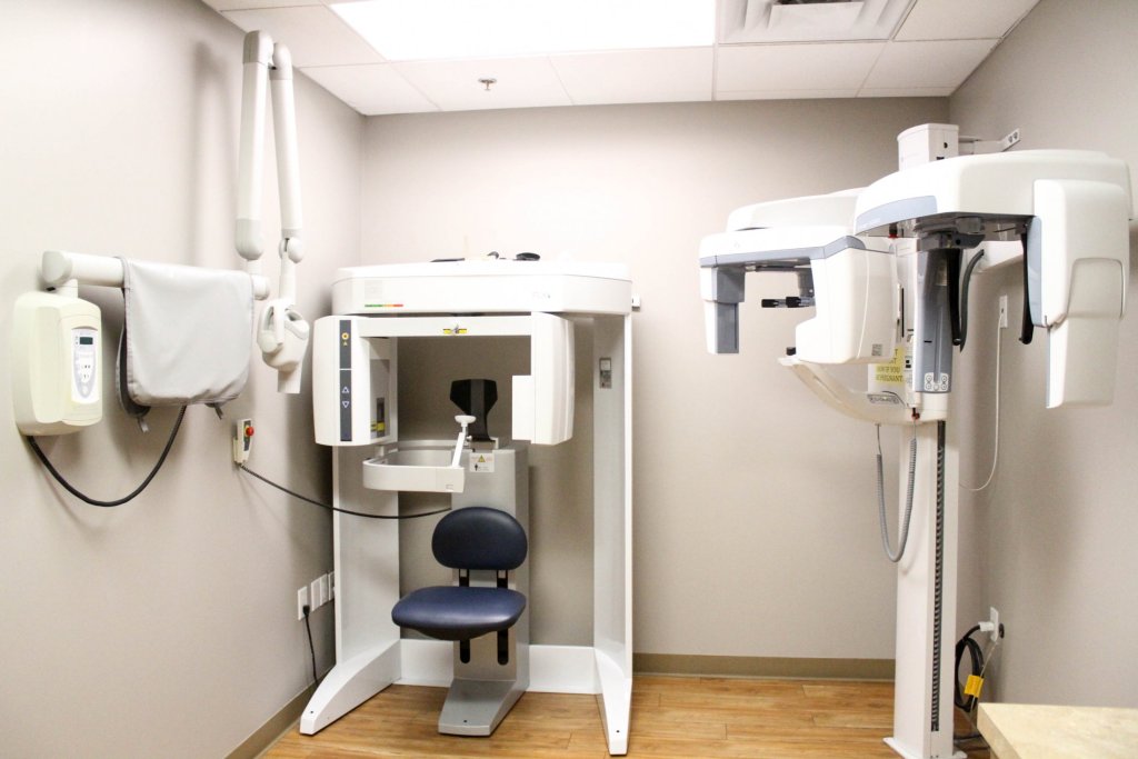 Dental X-ray room with two machines, chair, and cabinets
