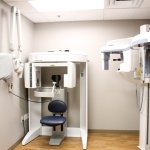 Dental X-ray room with two machines, chair, and cabinets