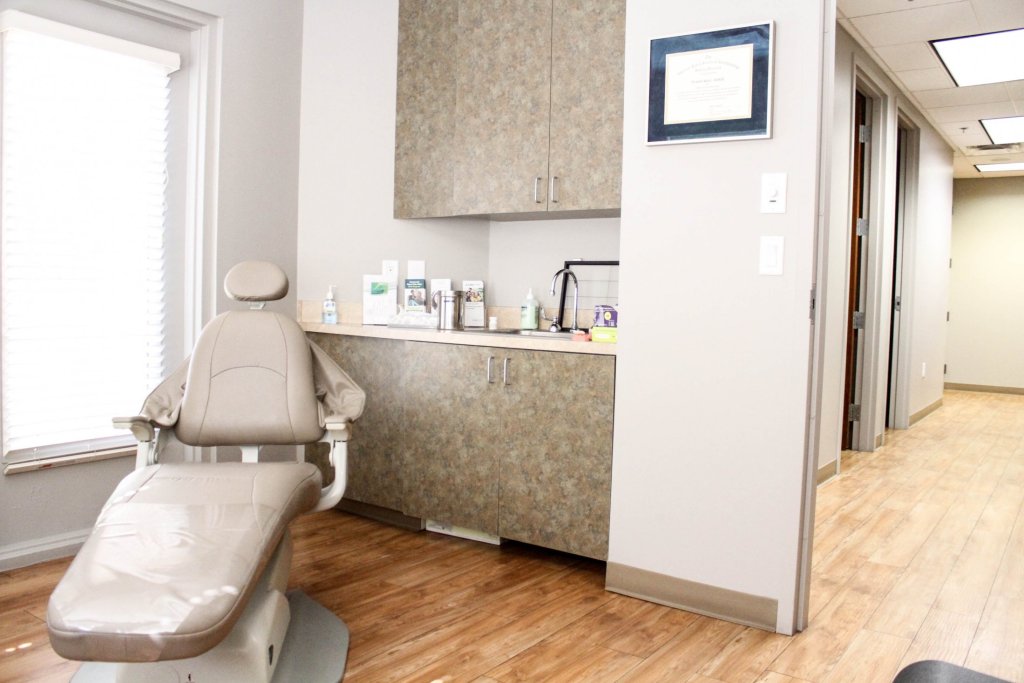 Dental treatment room with chair, cabinets, sink, and window