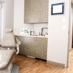 Dental treatment room with chair, cabinets, sink, and window