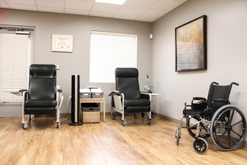 Room with two recliners, wheelchair, wooden floor, and wall art