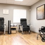 Room with two recliners, wheelchair, wooden floor, and wall art